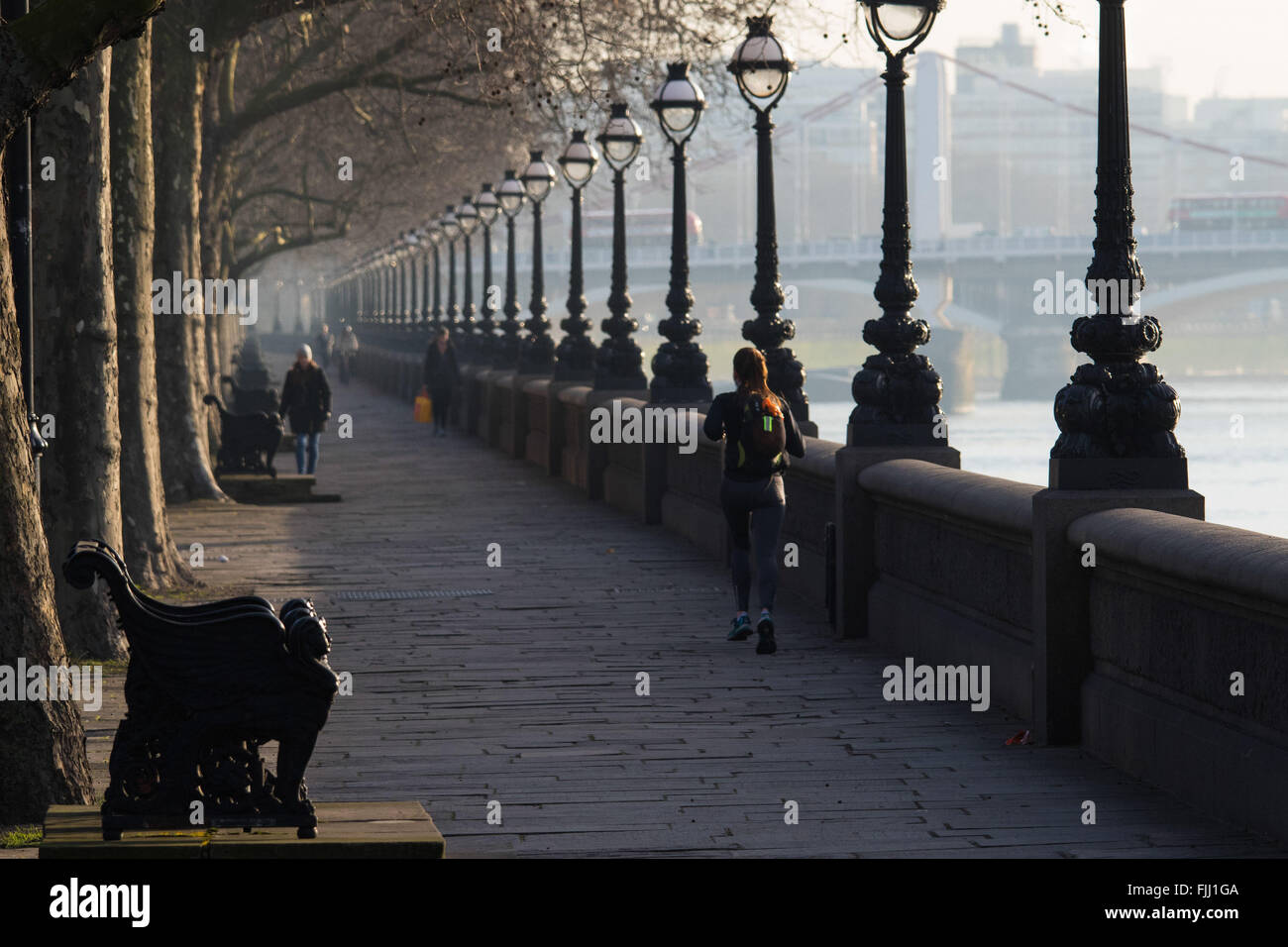 Un coureur se rend le long du côté de la Tamise sur Cheyne à pied comme le soleil se lève sur un matin froid Londres. Banque D'Images