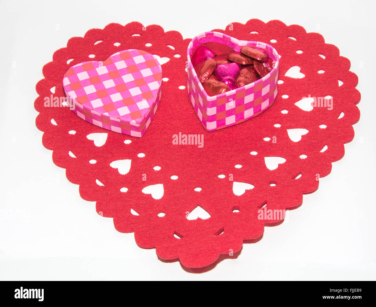 Une image montrant le concept de l'amour avec une boîte cadeau pleine de chocolats sur un fond en forme de coeur Banque D'Images