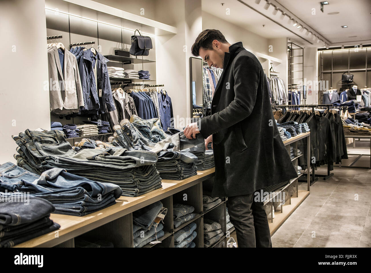 Vue latérale du jeune homme le choix du client en magasin de vêtements pour homme  chemise Photo Stock - Alamy