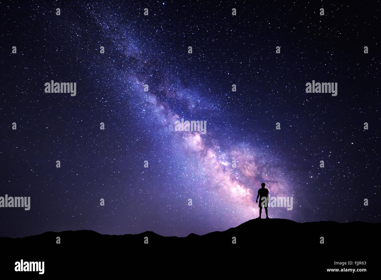 Paysage avec Voie Lactée. Ciel de nuit avec des étoiles et silhouette d'un homme heureux permanent sur la montagne. Banque D'Images