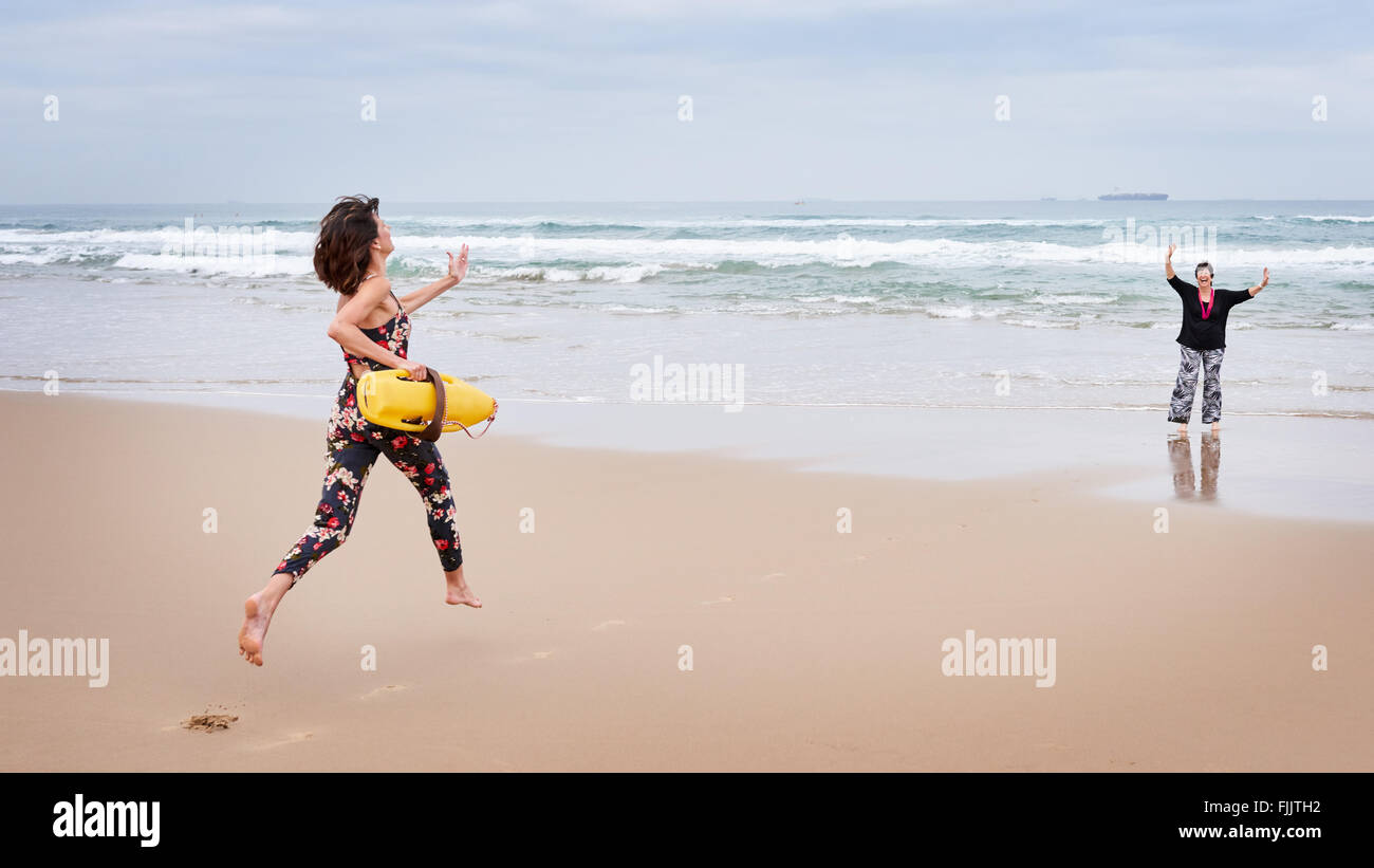 Mère fait semblant de nécessité au sauvetage par sa fille côté plage Banque D'Images