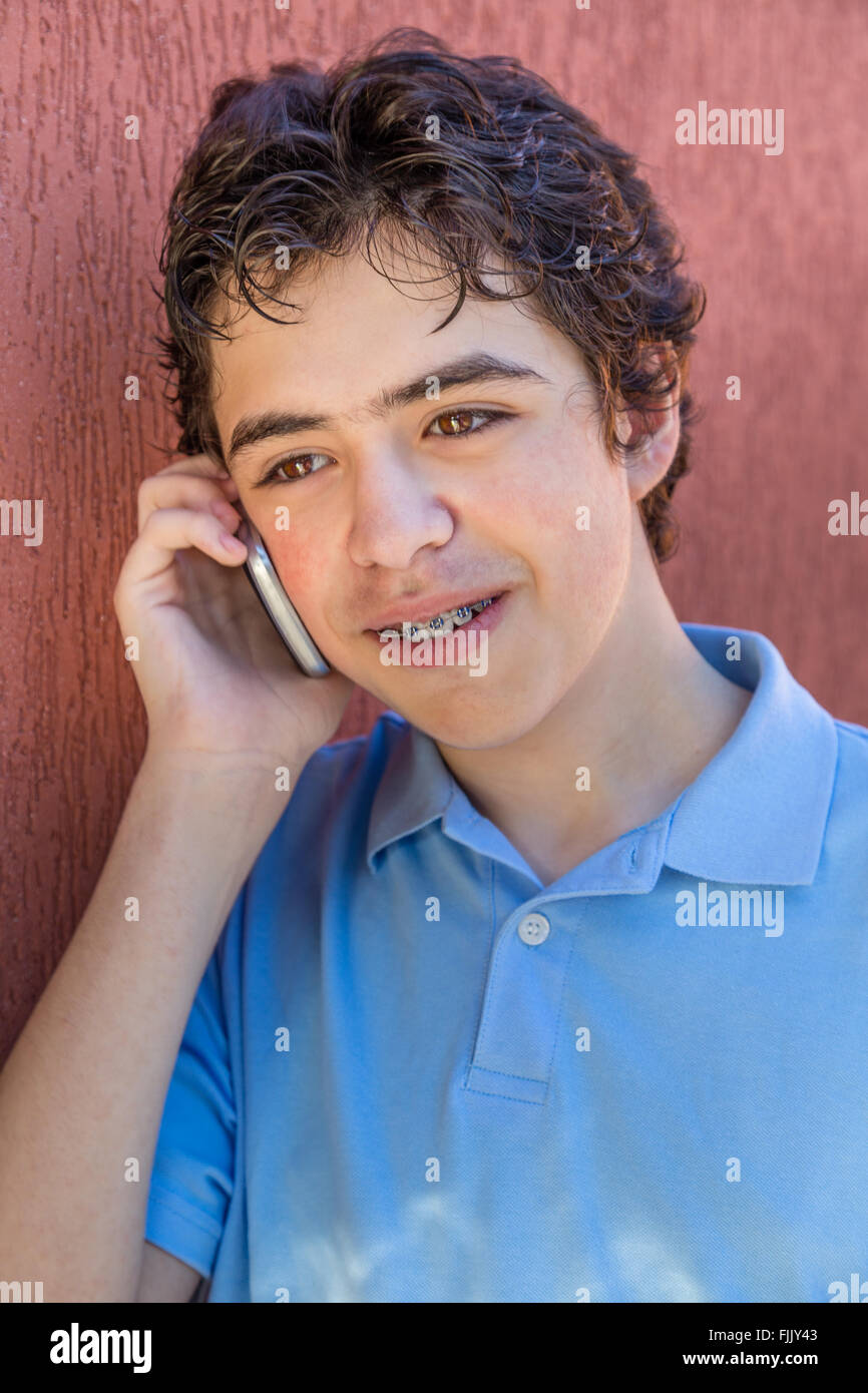 Jeune garçon souriant à bretelles tout en parlant sur mobilr phone Banque D'Images