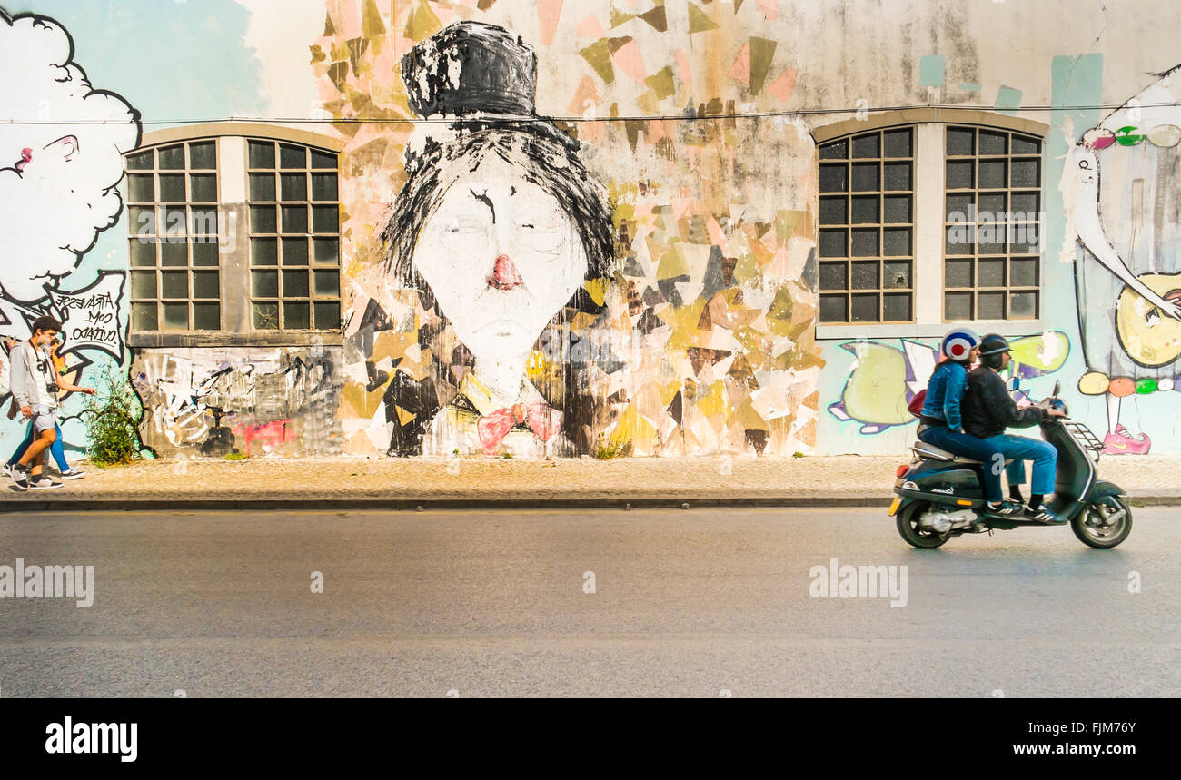 Scène de rue, façade avec graffiti, jeune couple en scooter Banque D'Images
