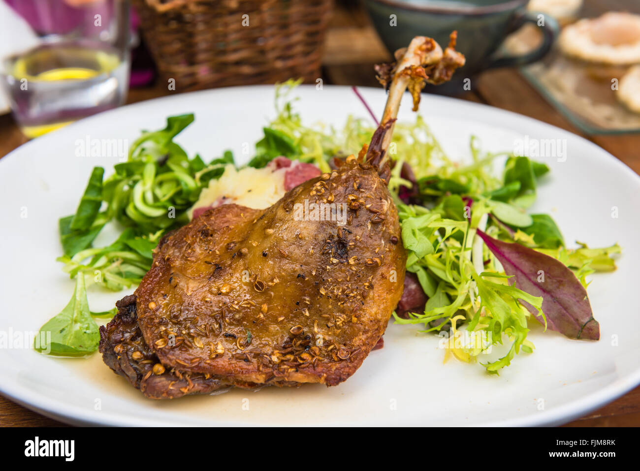 Plat d'une cuisse de canard rôti et salade verte sur une plaque blanche Banque D'Images