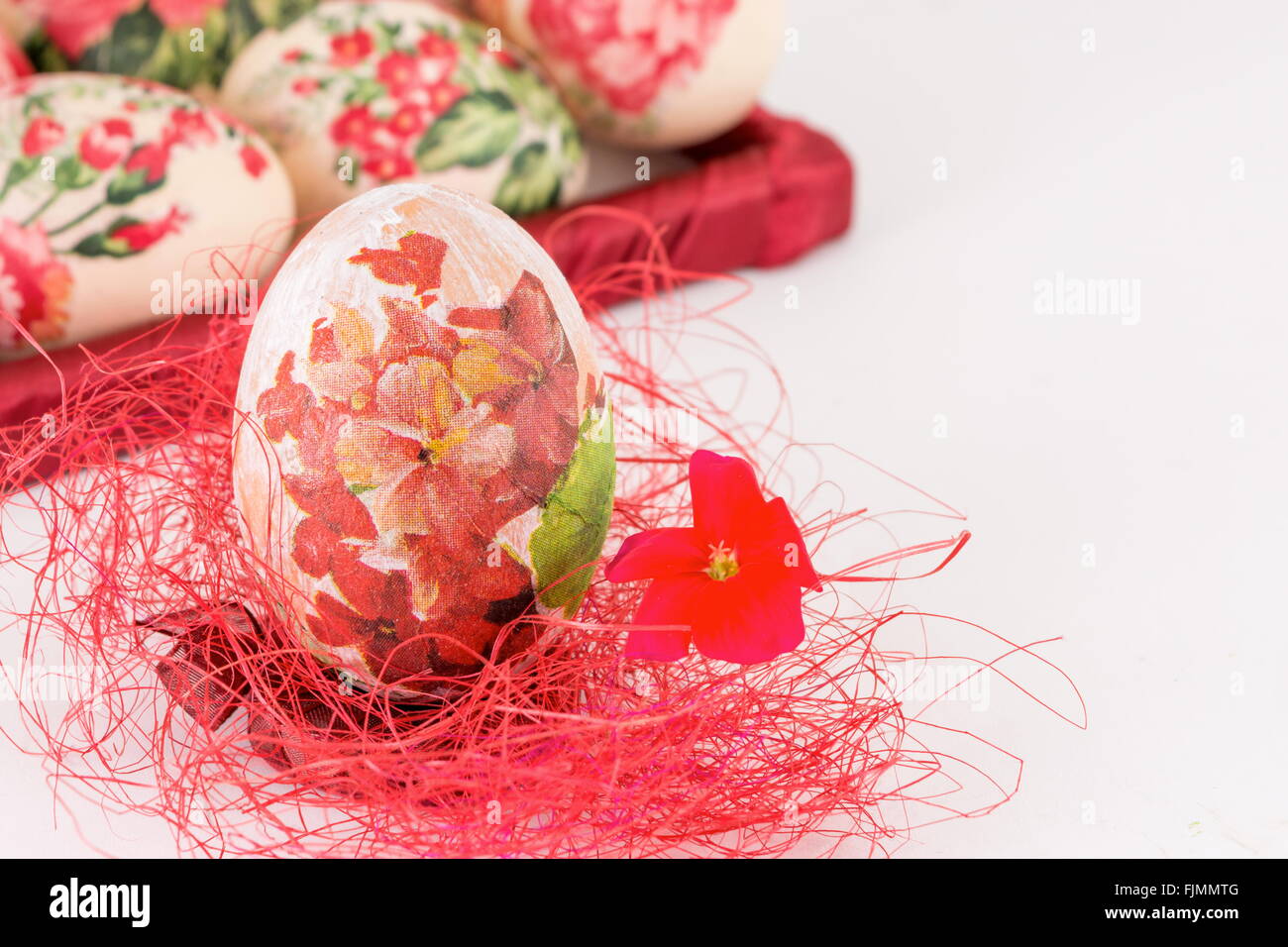 Oeufs de Pâques décorés Decoupage sur paille rouge Banque D'Images
