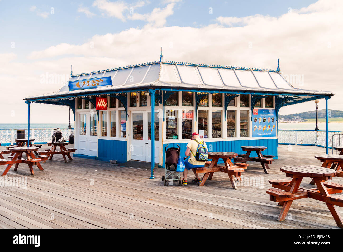 Croisière avec l'homme dans une poussette est assis à l'extérieur des océans café à la fin de la jetée de Llandudno la messagerie texte. Llandudno North Wales U.K. Banque D'Images