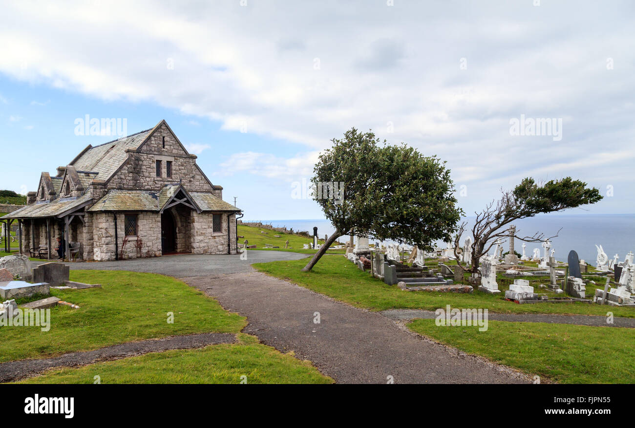 Les arbres tordus par le disque penchée à droite vers la mer d'Irlande dans le cimetière de Saint Tudno's Church, Great Orme, Llandudno Banque D'Images