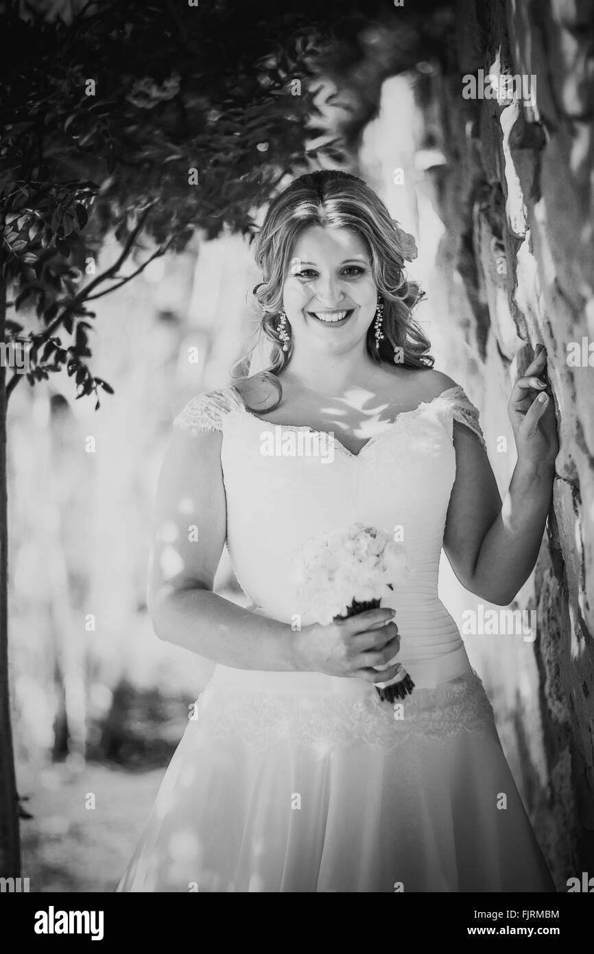 Beautiful happy élégante bride holding bouquet de fleurs sur un fond de mur de pierre Banque D'Images