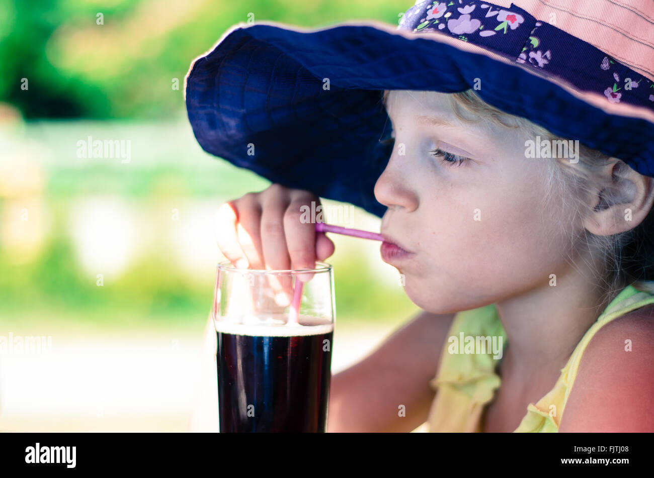 Belle petite fille avec de la paille de verre potable Banque D'Images