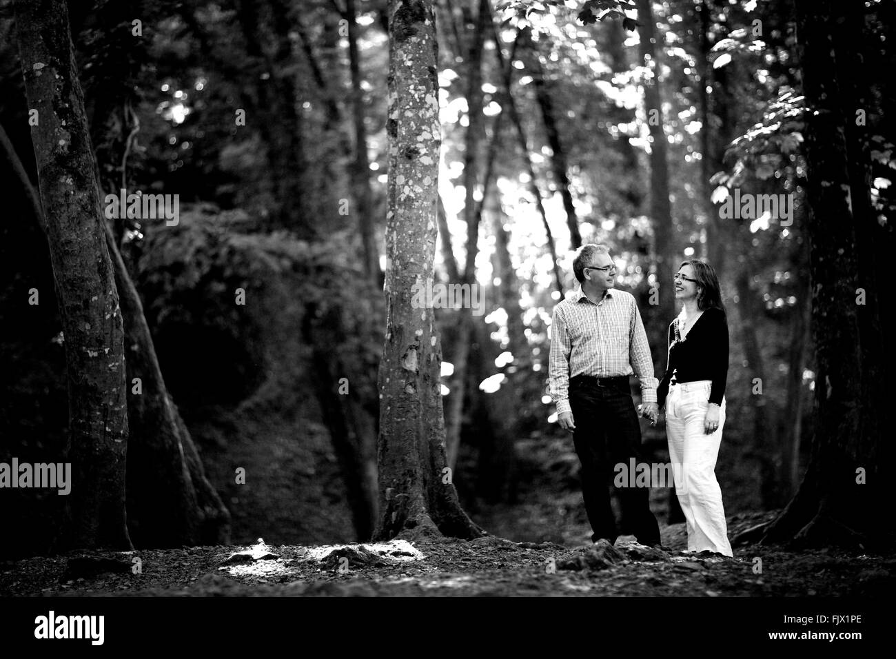 Couple dans les bois au milieu de la nature, tenant les mains, heureux, des sourires, de l'amour Banque D'Images