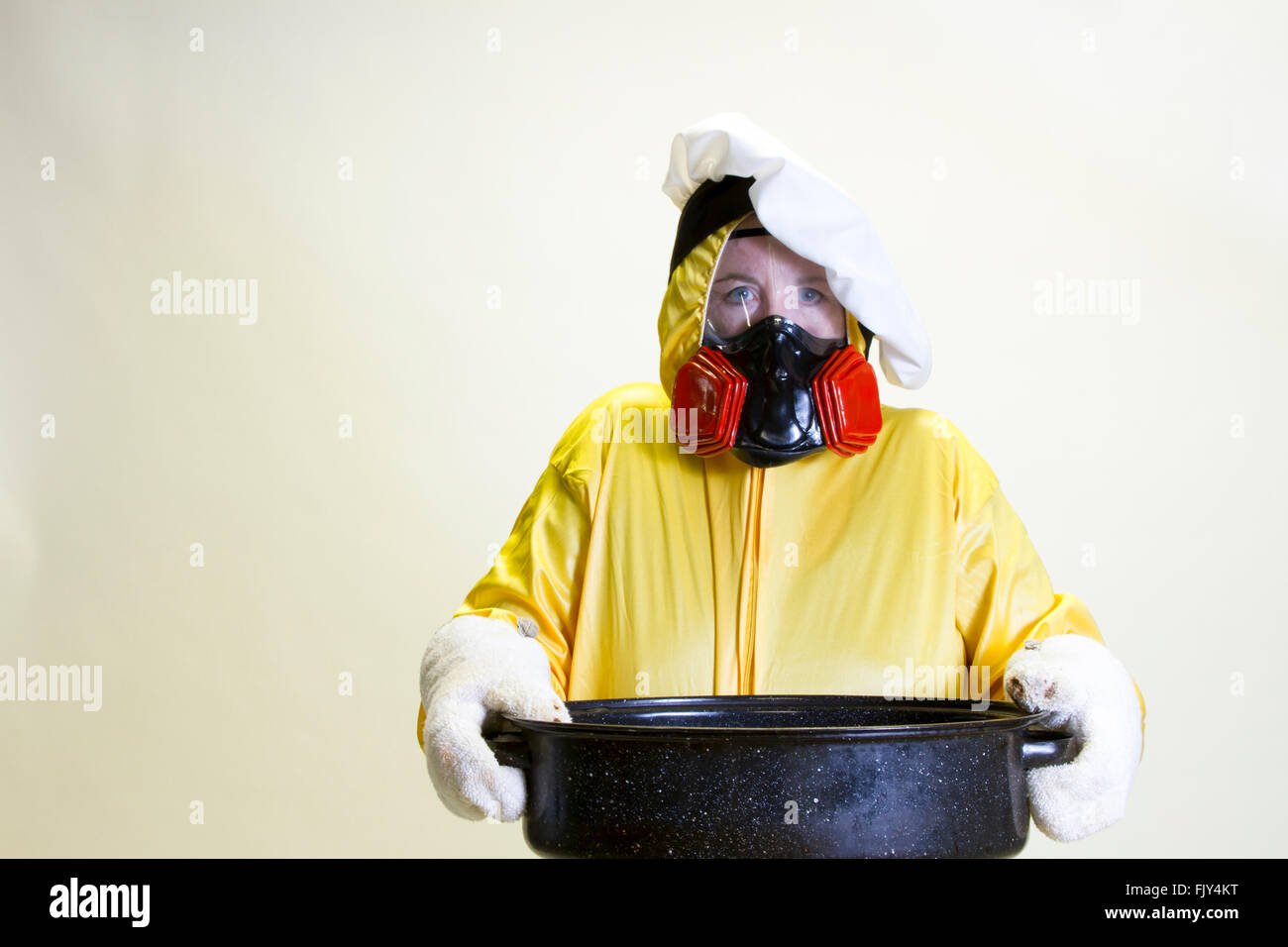 Femme mature en jaune et hazmat chef hat suit holding rôtissoire. Banque D'Images