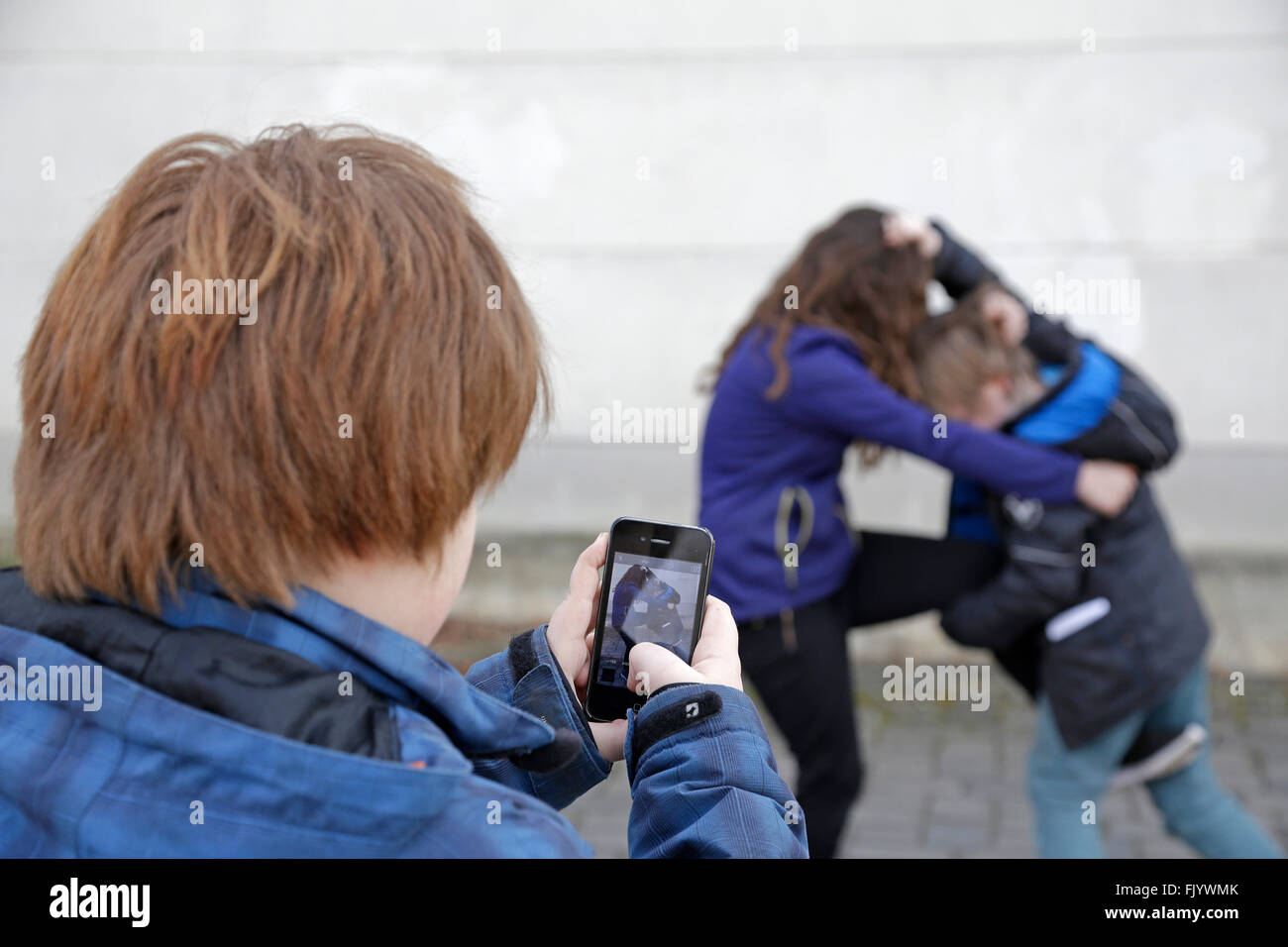 Deux enfants, un troisième combat faire video with smartphone Banque D'Images