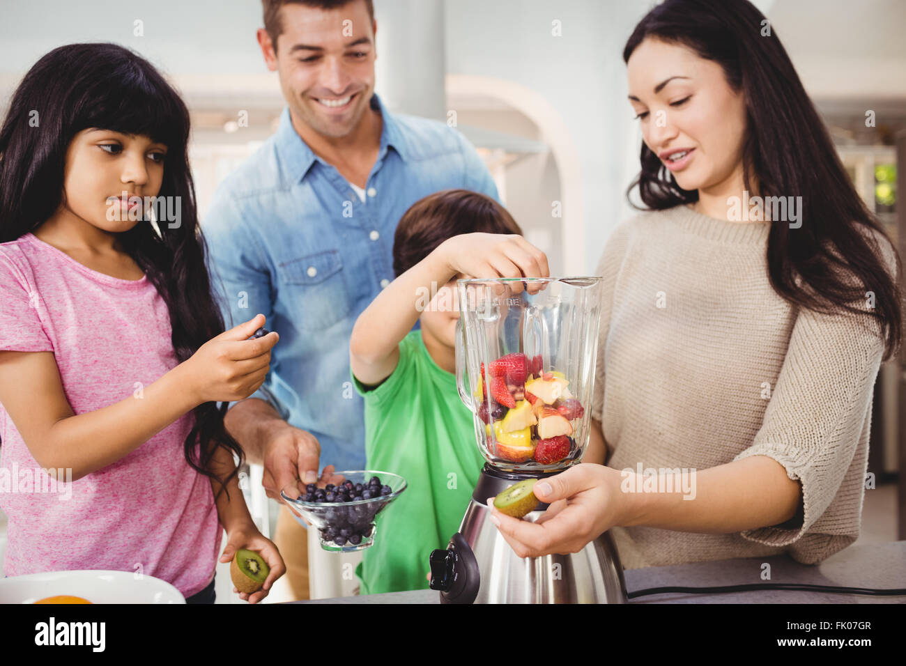 Famille heureuse la préparation de jus de fruits Banque D'Images