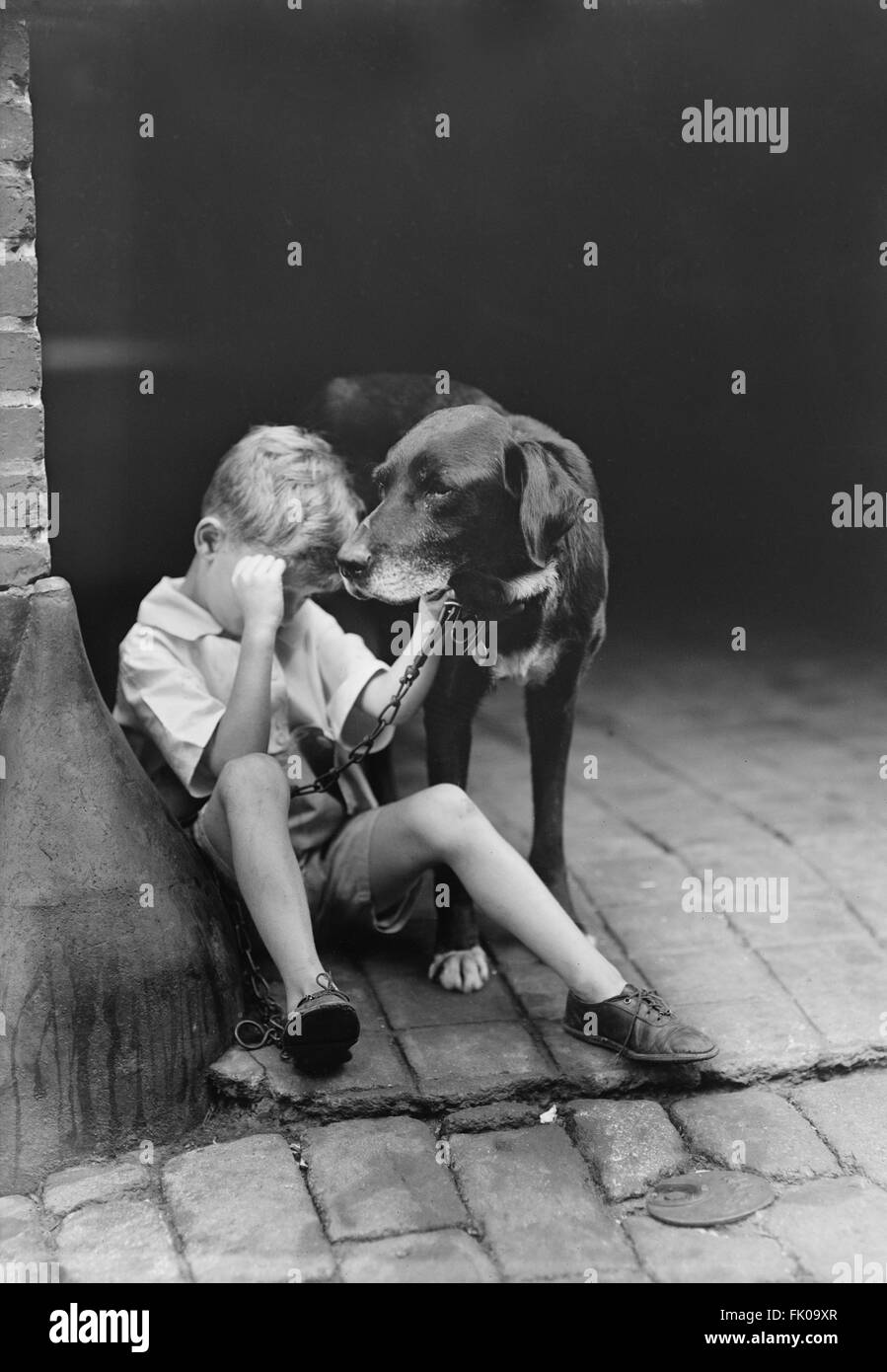 Triste garçon au chien, USA, vers 1921 Banque D'Images