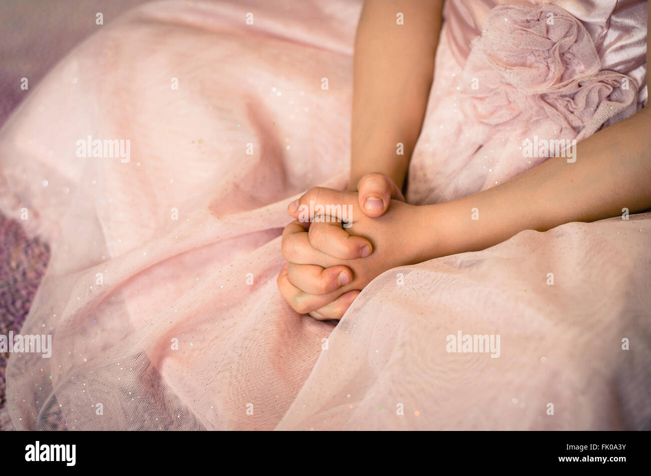 Prier avec les mains sur l'enfant robe rose de droit Banque D'Images