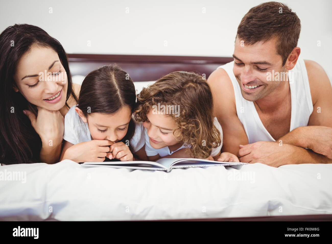 Livre de lecture enfants heureux avec les parents on bed Banque D'Images
