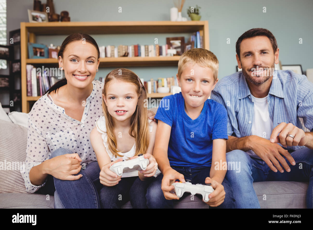 Smiling Children playing video games avec les parents Banque D'Images