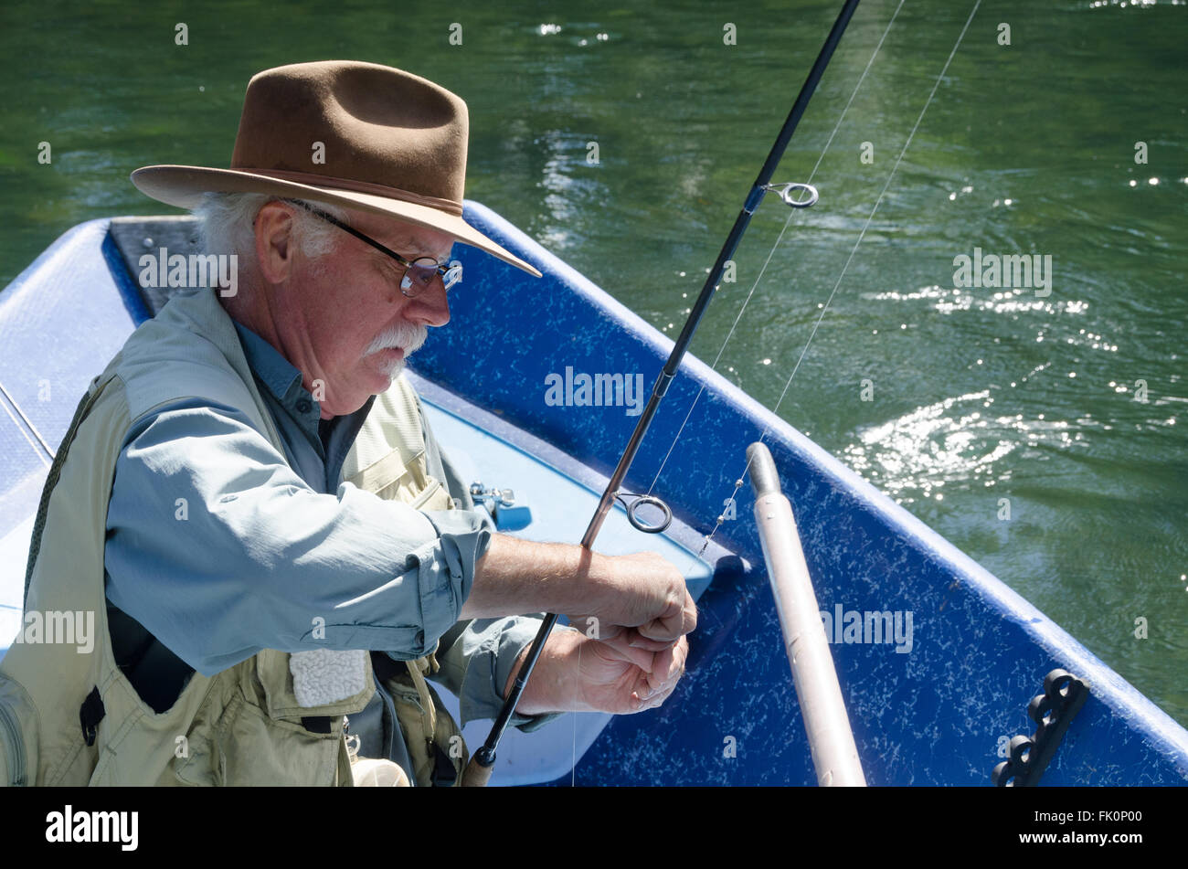 A senior man se concentre alors qu'il se prépare sa ligne pour la pêche. Banque D'Images