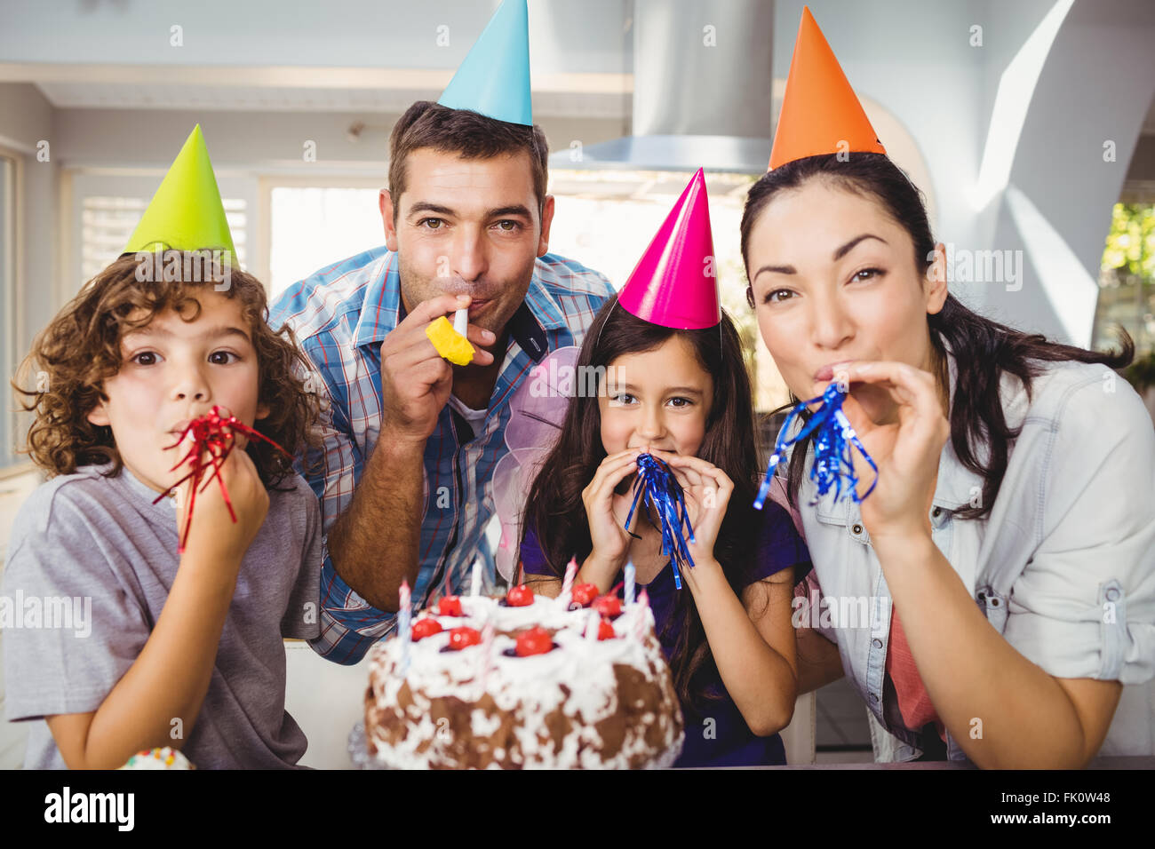 Happy Family blowing party horn lors d'anniversaire Banque D'Images