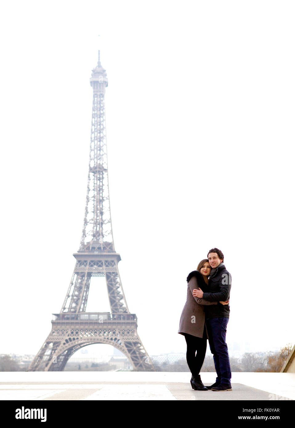 Les jeunes et dans l'amour brunette couple in front of Eiffel tower, Paris, au Trocadéro sur la ville pendant la journée - hugging Banque D'Images