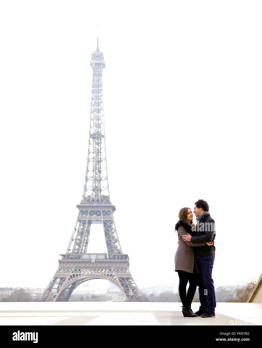 Les jeunes et dans l'amour brunette couple in front of Eiffel tower, Paris, au Trocadéro sur la ville pendant la journée - hugging Banque D'Images