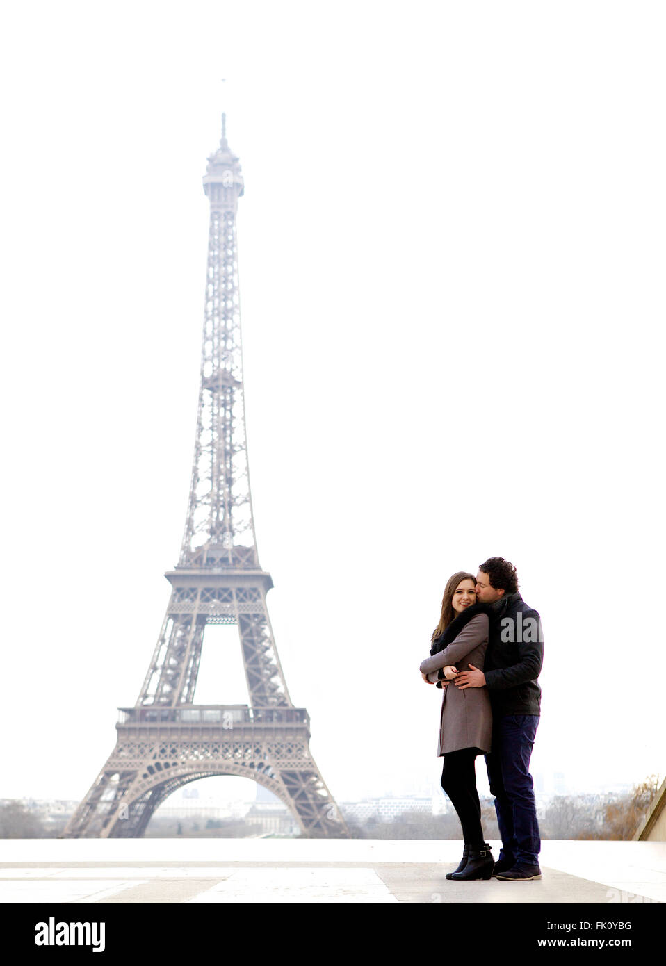 Les jeunes et dans l'amour brunette couple in front of Eiffel tower, Paris, au Trocadéro sur la ville pendant la journée - holding Banque D'Images