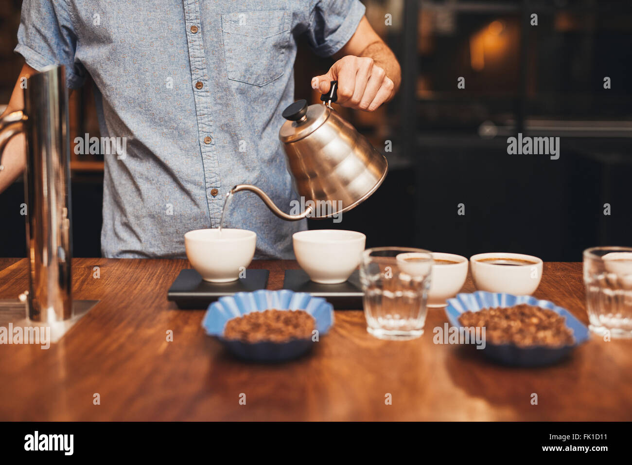 Homme verser de l'eau dans une tasse à café sur une échelle numérique Banque D'Images