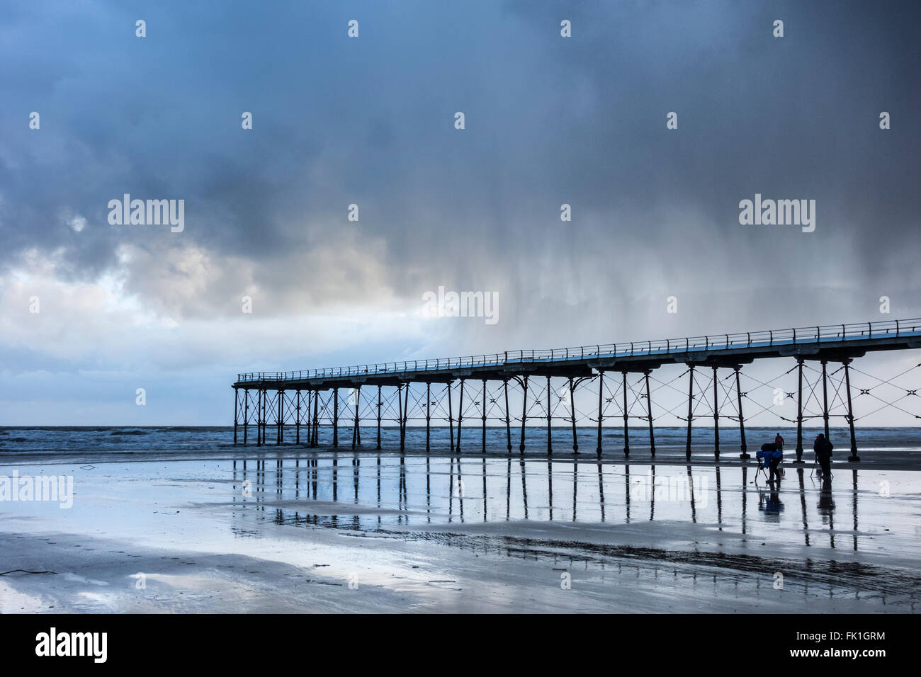 Saltburn par la mer, North Yorkshire, Angleterre, Royaume-Uni. Photographes sous la jetée de Saltburn comme un rideau de pluie passe. Banque D'Images