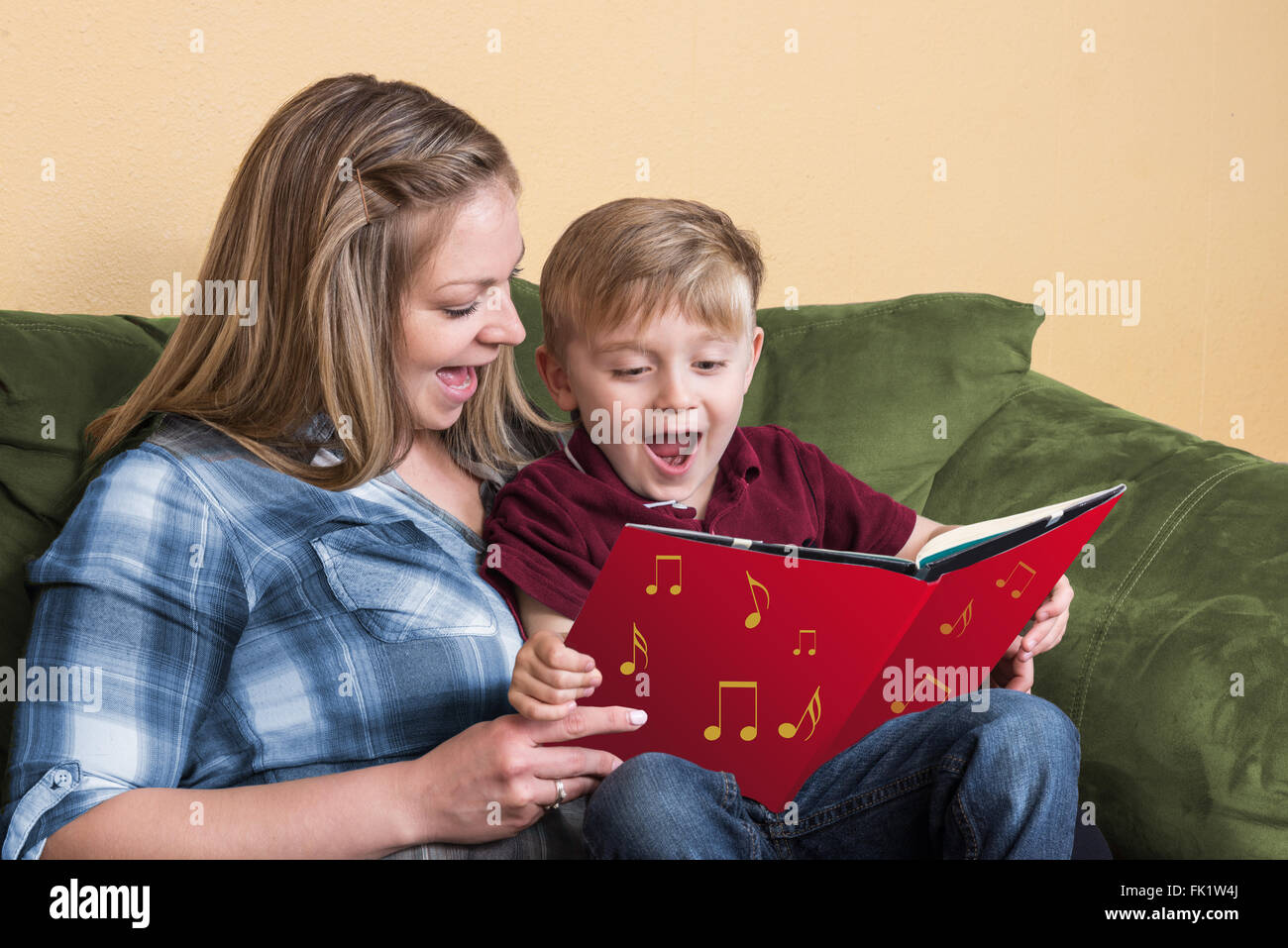 Un jeune enfant s'apprête à lire en chantant avec sa mère à l'aide d'un livre basé sur une chanson. Banque D'Images