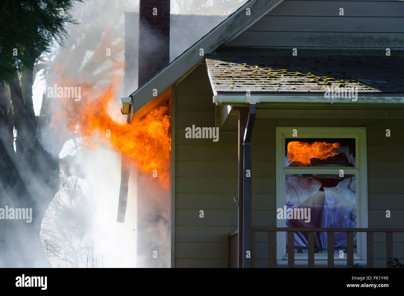 Lèche flambante de par la fenêtre d'une maison entourée d'une épaisse fumée noire Banque D'Images