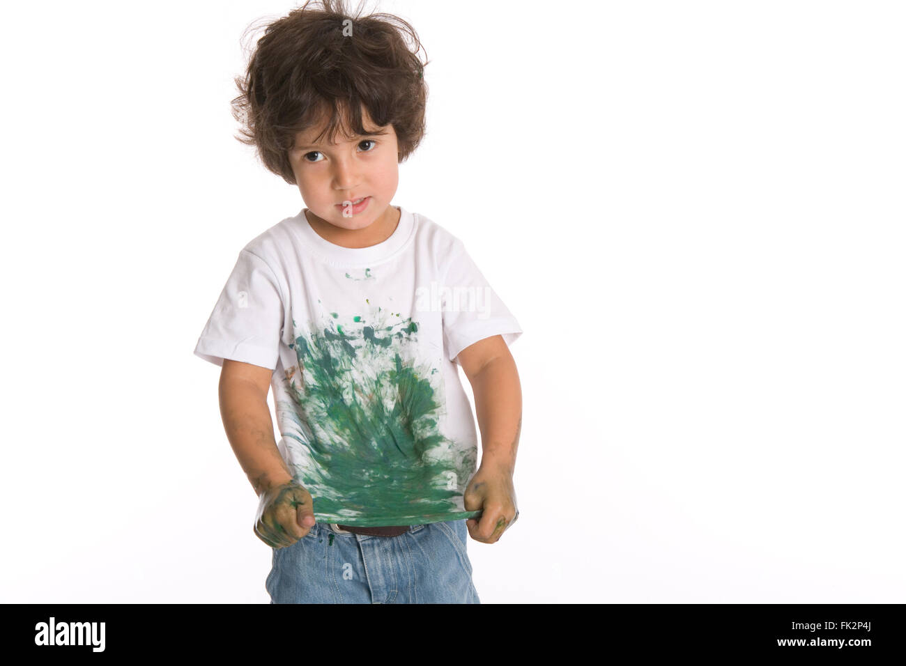 Petit garçon avec un coupable Expression montre sa chemise pleine de Peinture sur fond blanc Banque D'Images
