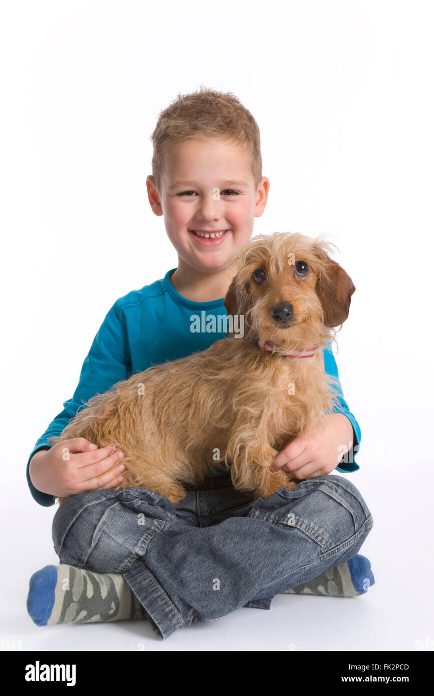 Petit garçon avec son chien sur ses genoux sur fond blanc Banque D'Images