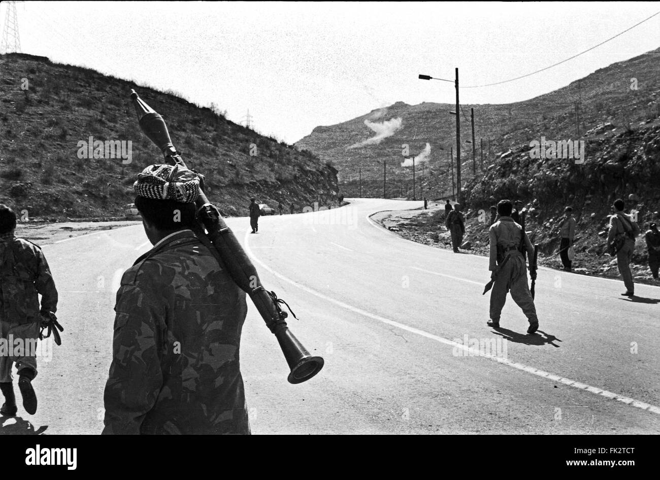 Près de Zakho, dans le nord de l'Irak, le Kurdistan. Mars 1991. Combattants du Front du Kurdistan irakien avec frontline aller vers les forces gouvernementales lors du soulèvement par les Kurdes contre les forces de Saddam Hussein. À partir de l'explosion des roquettes tirées par l'attaque d'hélicoptères de combat peut être vu dans les collines au centre du châssis. Banque D'Images