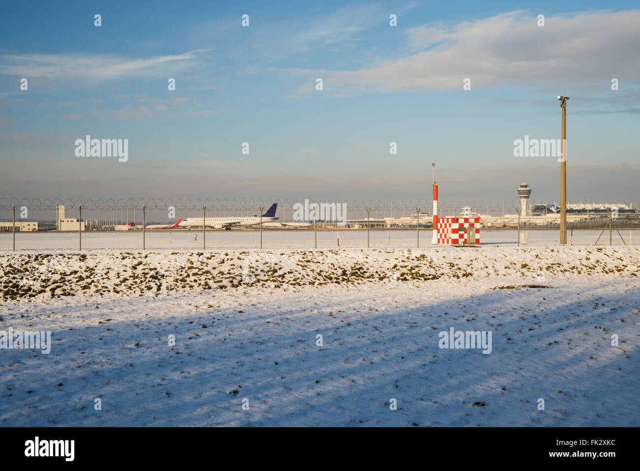 Vue de la barrière de sécurité et des avions sur la piste et les terminaux de l'aéroport de Munich à la fin de l'après-midi du soleil en hiver Banque D'Images