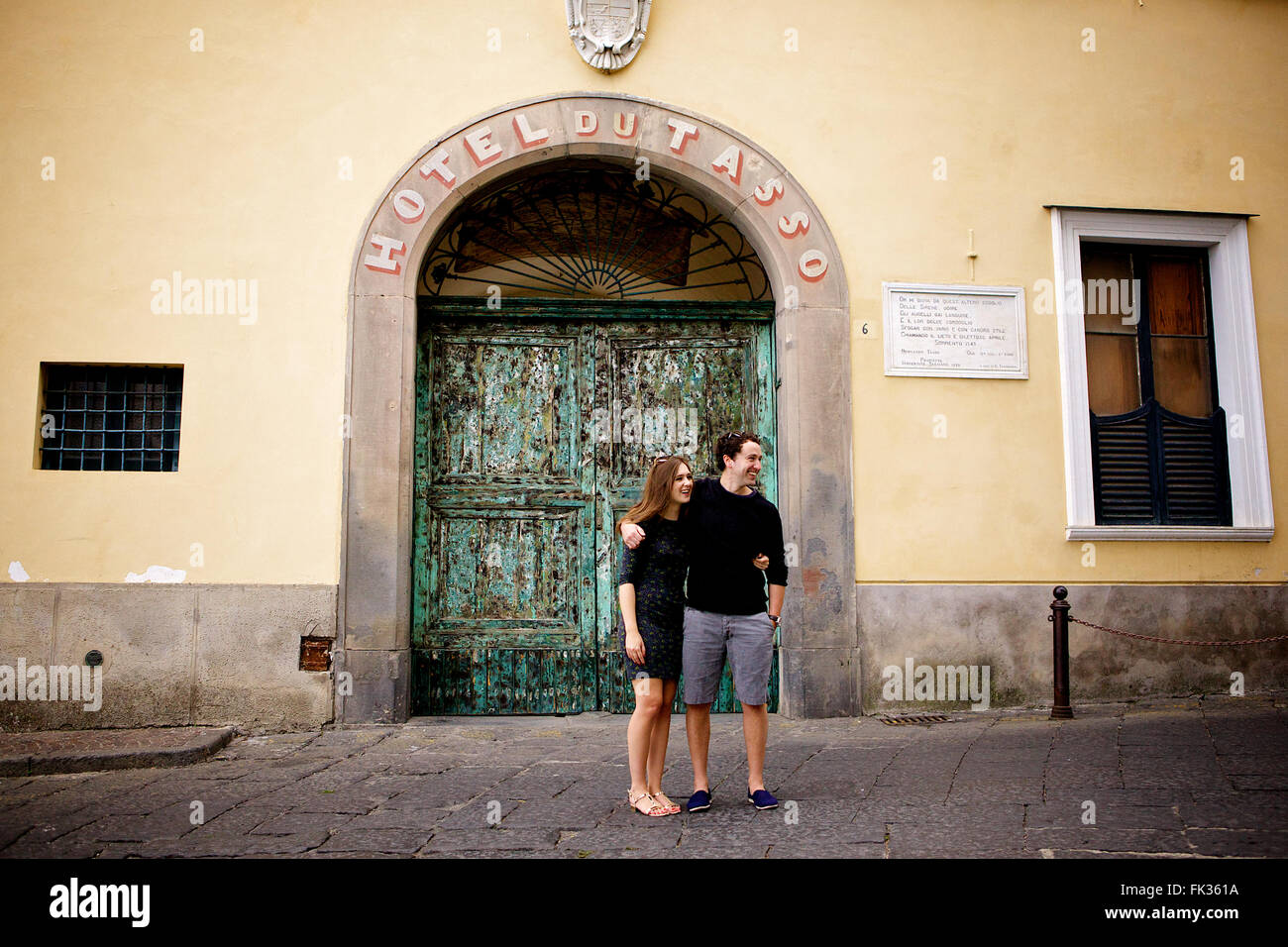 Un jeune couple dans l'amour brunette en face d'un merveilleux, vieux bâtiment italien, méditerranéen, grand portail vert archway Banque D'Images