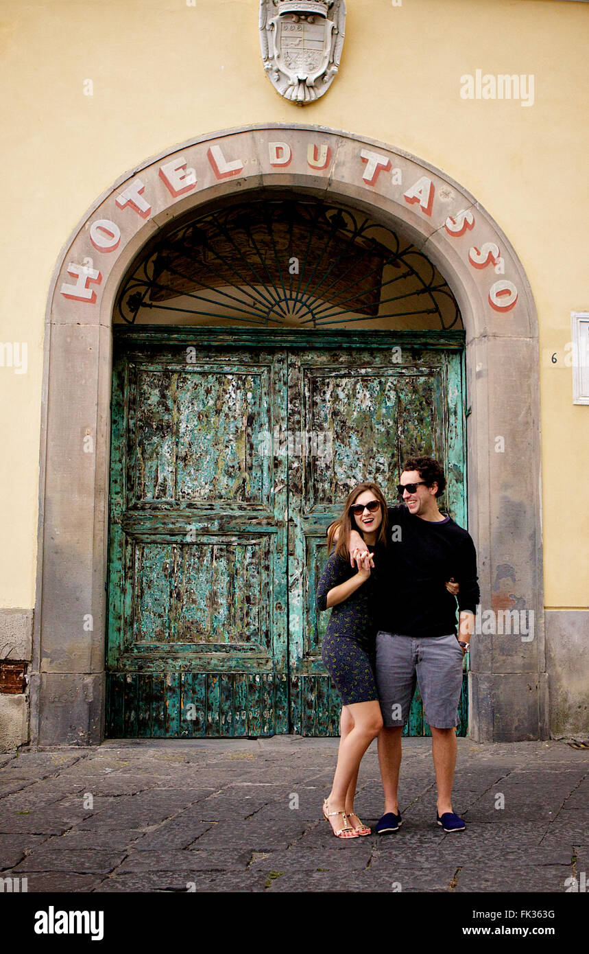 Un jeune couple dans l'amour brunette en face d'un merveilleux, vieux bâtiment italien, méditerranéen, grand portail vert archway Banque D'Images