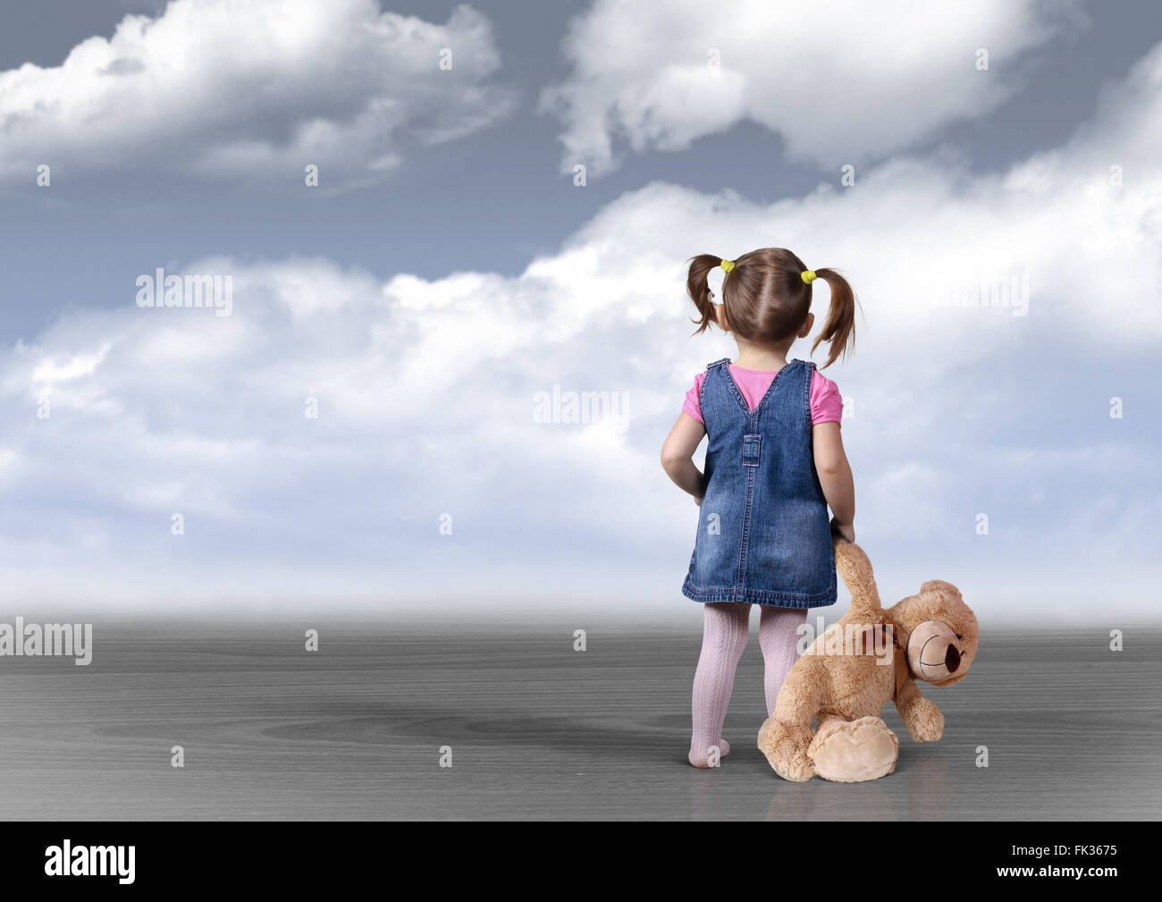Fille enfant avec ours en peluche dans la distance, à la vue de dos, concept perception Banque D'Images