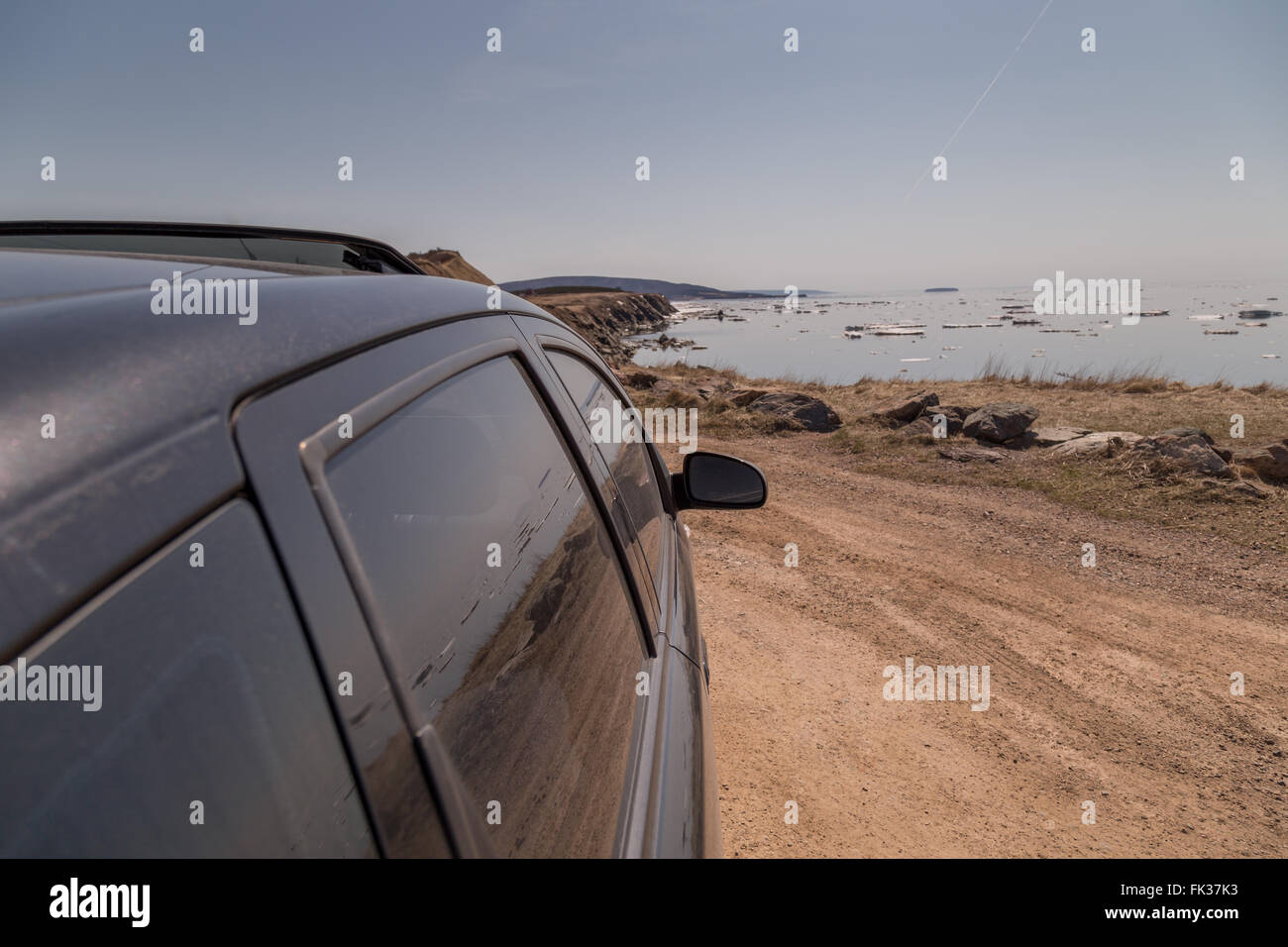 Une voiture noire s'arrêta à côté d'un chemin de terre le long du Cabot Trail en Nouvelle-Écosse, côte est du Canada, au printemps. Chunk Banque D'Images
