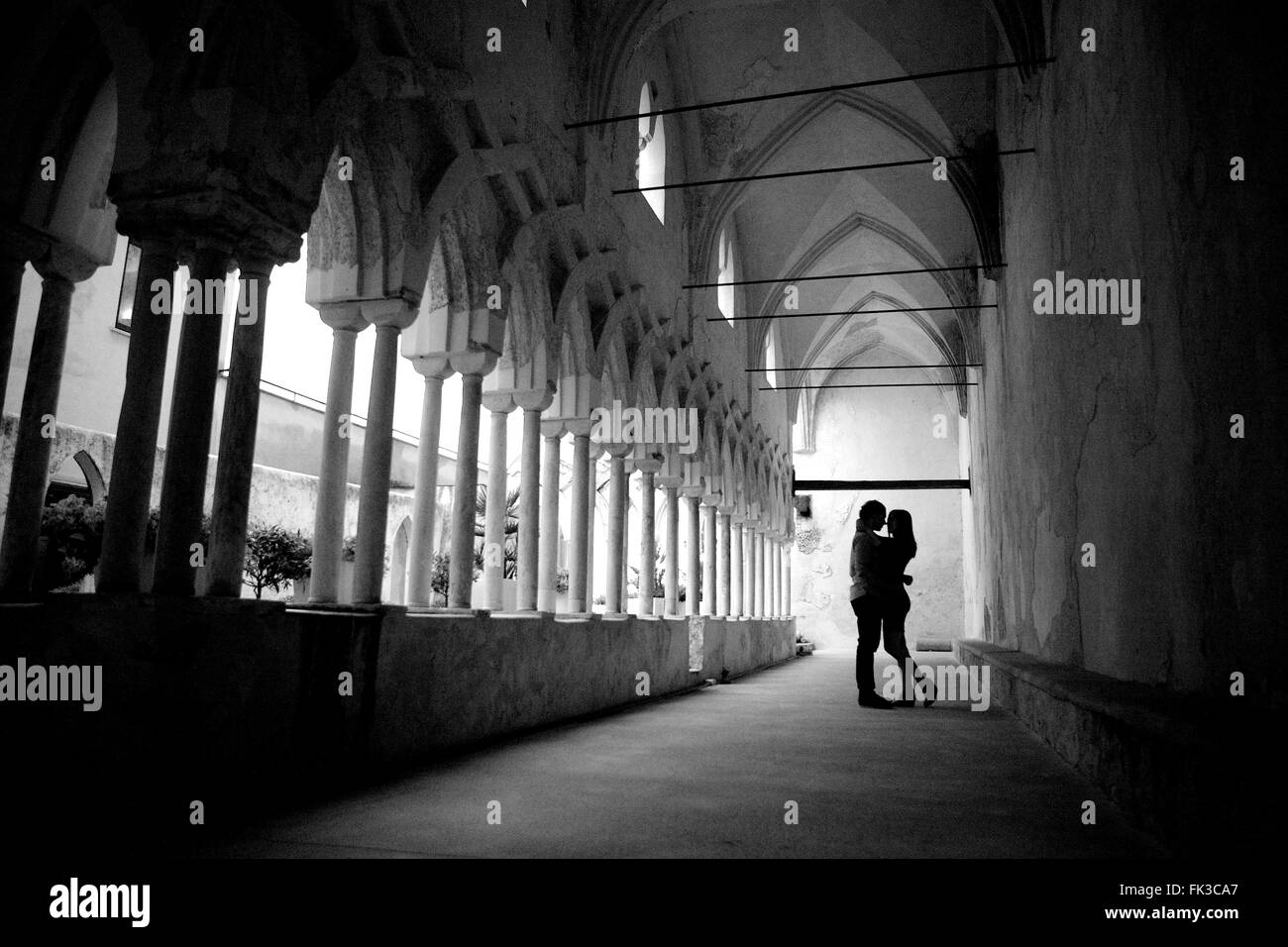 Silhouette d'un jeune couple dans un long couloir d'un ancien monastère. Arcs traditionnels en laissant la lumière, l'Italie, l'art Banque D'Images