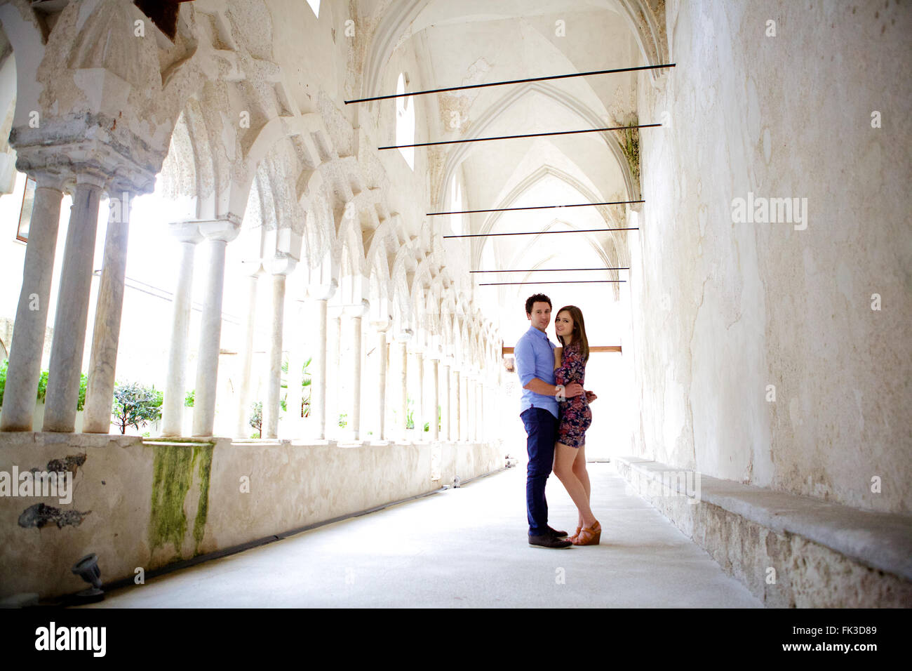 Un jeune couple brunette et dans l'amour dans le parc d'une ancienne et traditionnelle italienne historique, magnifique monastère, de grandes fenêtres Banque D'Images