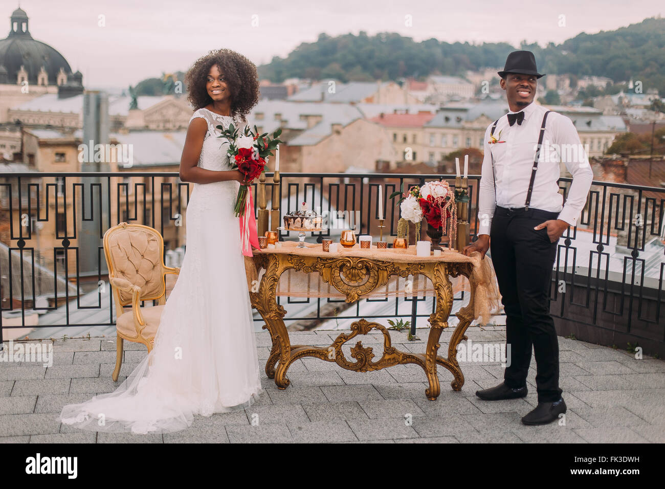Heureux nouveaux mariés noir souriant joyeusement sur la terrasse près de la table de mariage Banque D'Images