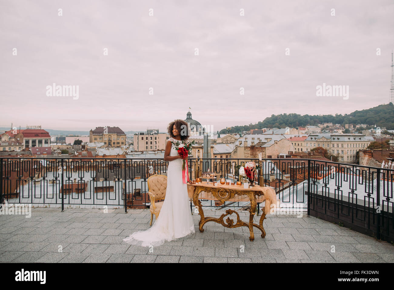 Jolie mariée africaine avec bouquet de mariage en mains debout sur la terrasse Banque D'Images