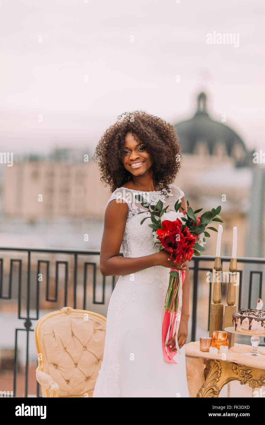 Heureuse mariée noir bouclés sur le toit en souriant. Jour de mariage Banque D'Images