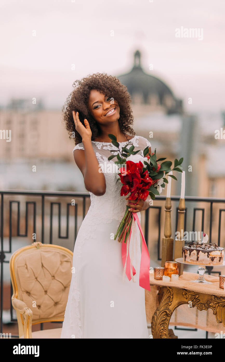 Happy black mariée corrige ses cheveux et sourit. Jour de mariage Banque D'Images