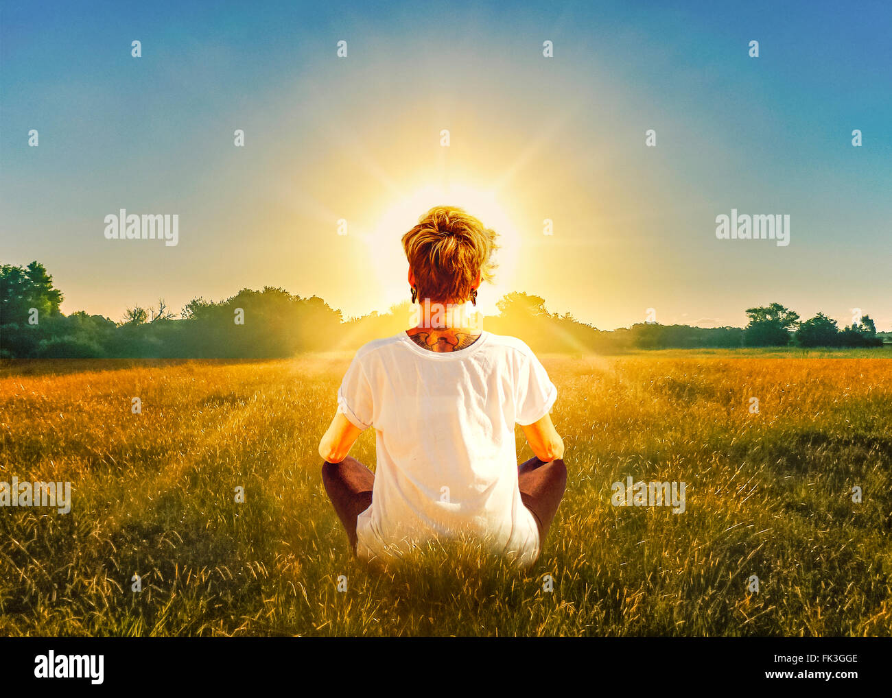 Femme assise devant le coucher de soleil Banque de photographies et d