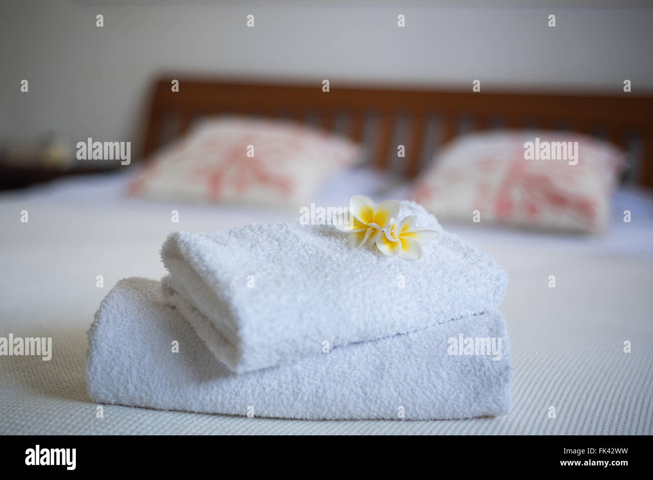 Fleurs de frangipanier sur les serviettes dans la chambre d'hôtel avec lit double en arrière-plan Banque D'Images