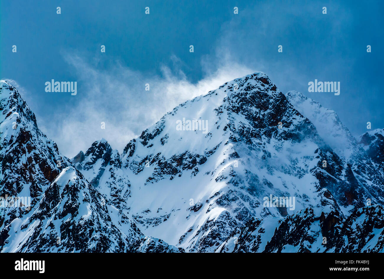 Neige tourbillonnante pris dans la lumière sur un sommet de montagne orageux en Autriche. Banque D'Images