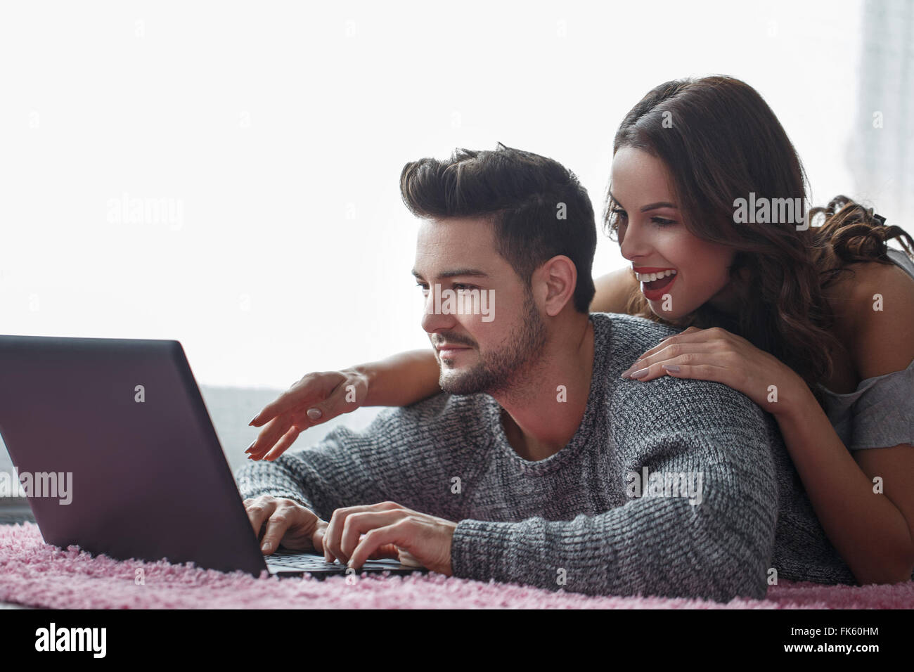 Jeune couple avec coffre allongé sur un tapis, la technologie wi-fi Banque D'Images