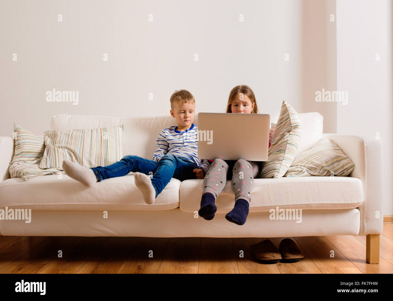 Enfants à la maison assis sur un canapé, jouer avec coffre Banque D'Images