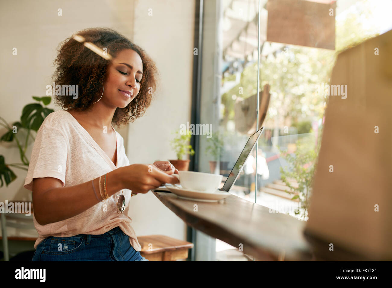 Shot of young African woman sitting in a cafe et boire du café. Femme africaine avec coffre le café au restaurant. Banque D'Images